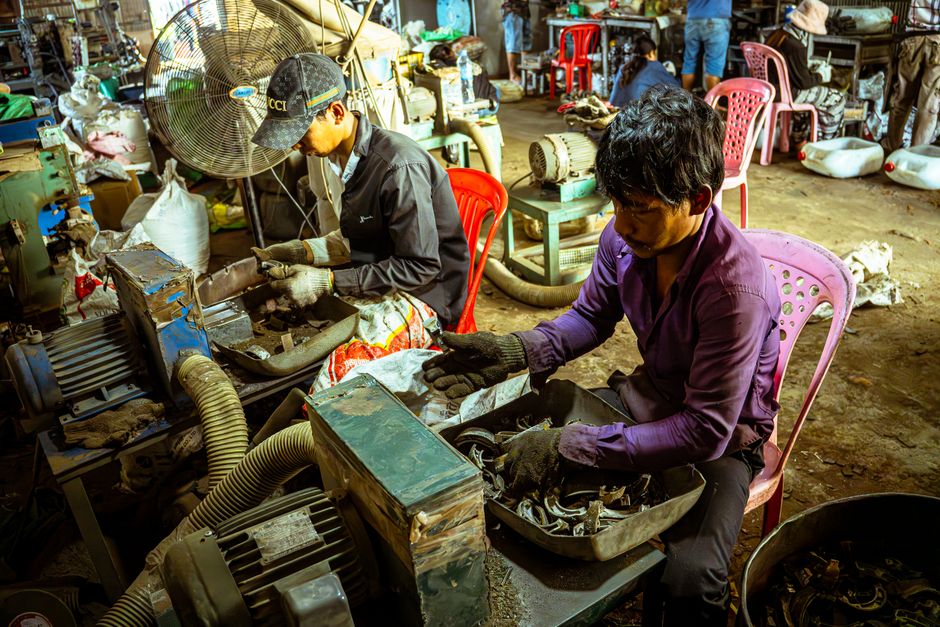 Men working with machinery in an industrial workshop, surrounded by tools and equipment.